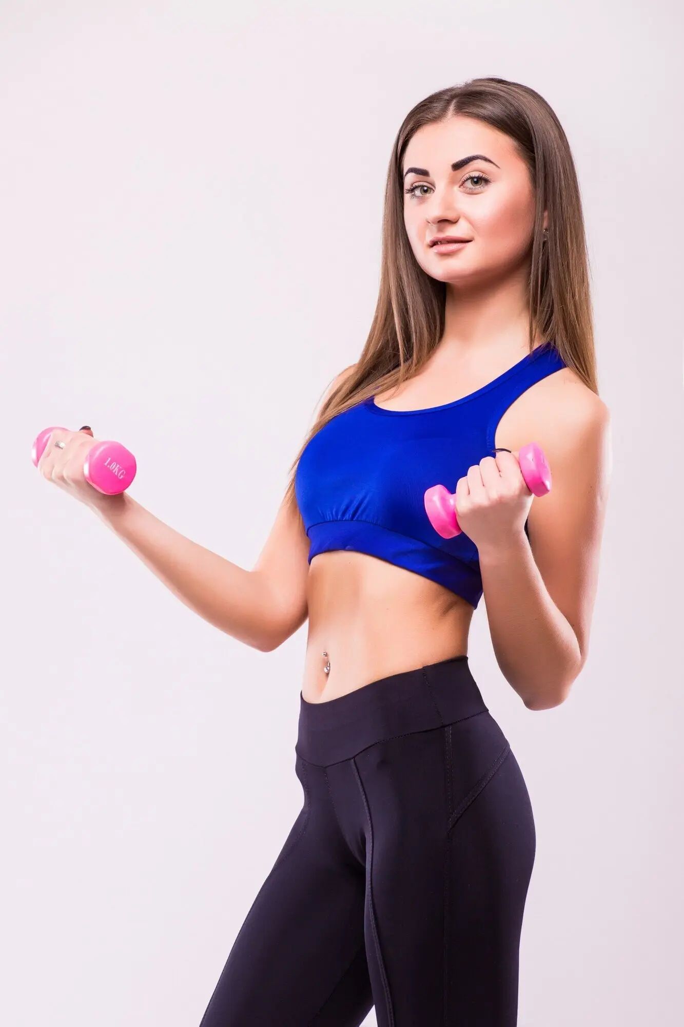 Здоровая женщина-латиноамериканка выполняет упражнения с гантелями на белом фоне. Концепция фитнеса и тренажерного зала.