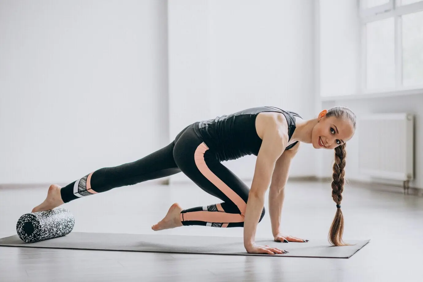 Женщина занимается йогой на коврике.