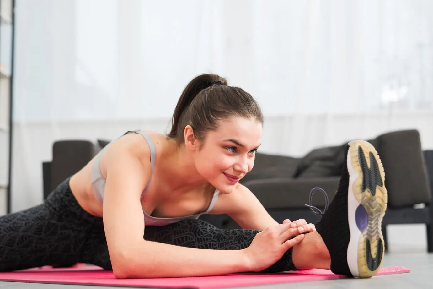 Девушка занимается растяжкой у себя дома.